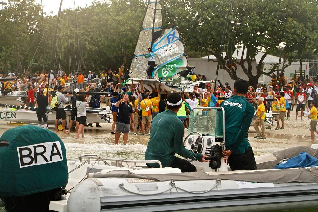 Martine Grael and Kahena Kunze (BRA) are given a heroines’ welcome as they come ashore in Brazil after winning the Gold Medal in the 49errFX class on the last leg of the course. 206 Olympic Sailing Regatta © Richard Gladwell www.photosport.co.nz